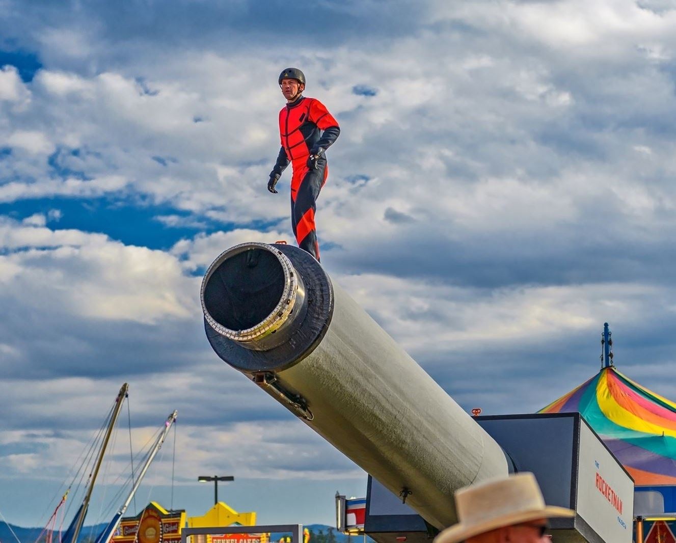 Man in a safety suit standing at the end of a giant, human-sized rocket