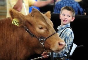 Small boy standing next to his cow smiling