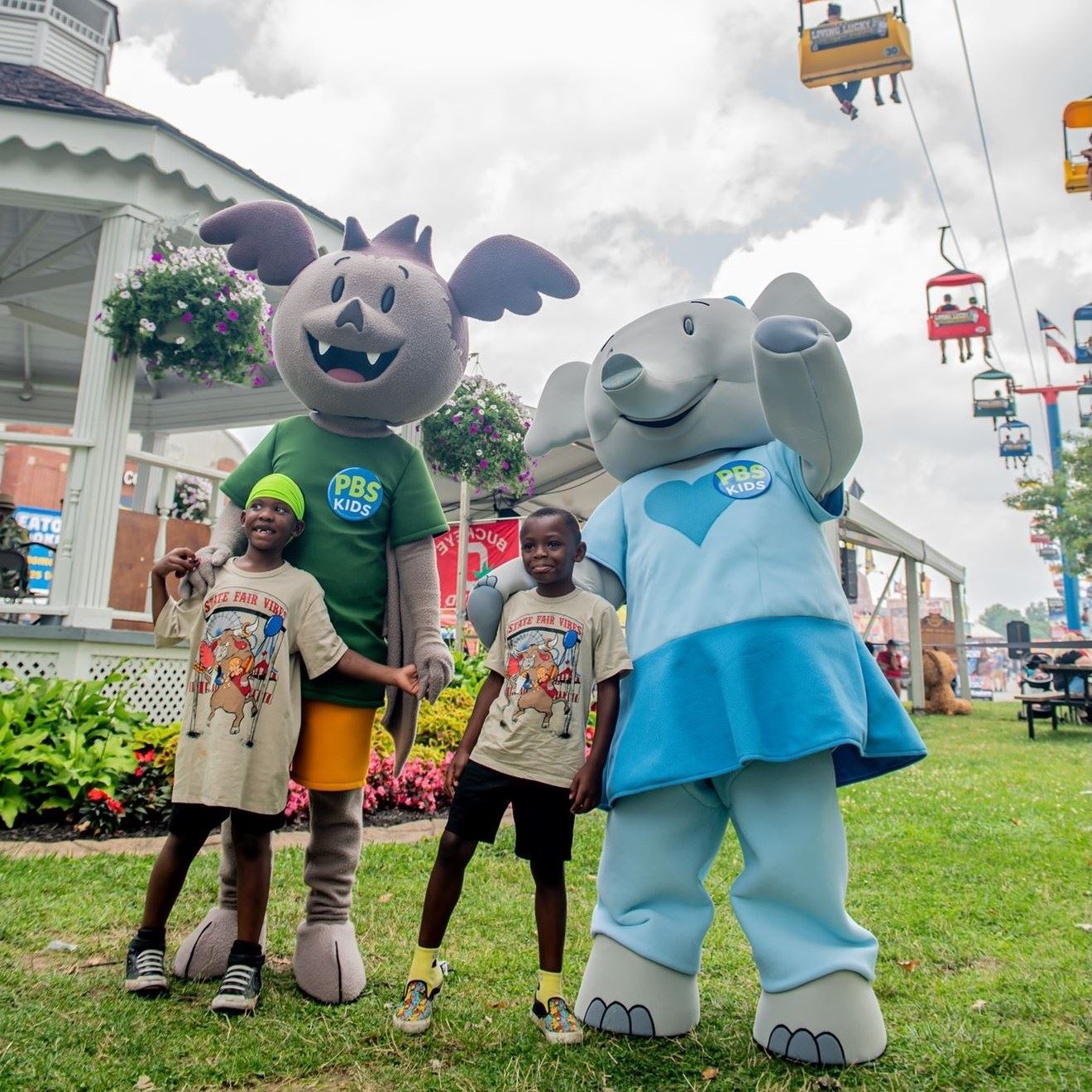 Two children standing with posed PBS characters during WOSU Kids Day at the Ohio State Fair.