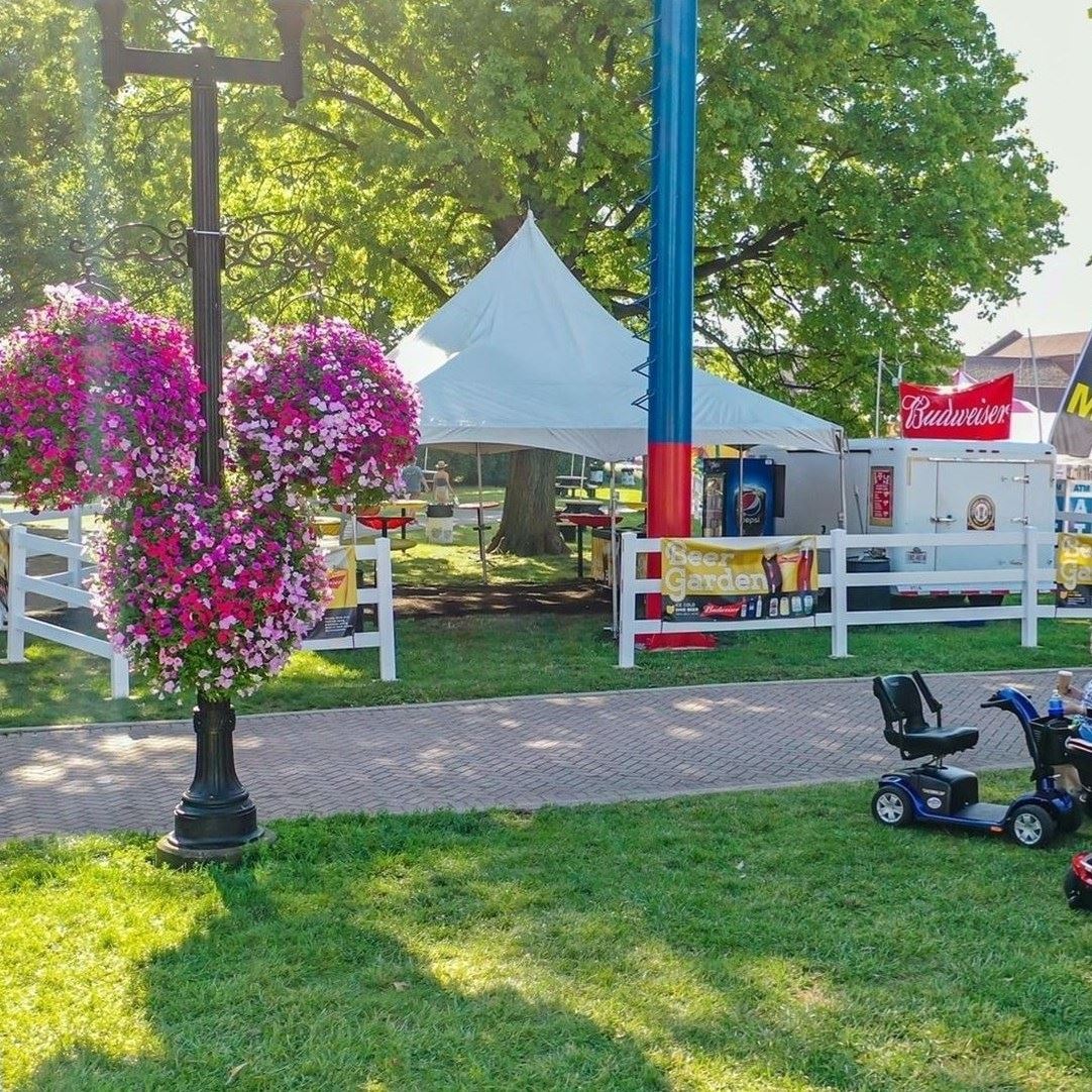 Hanging flowers at the Ohio State Fair with motorized accessibility scooter sitting in the grass.