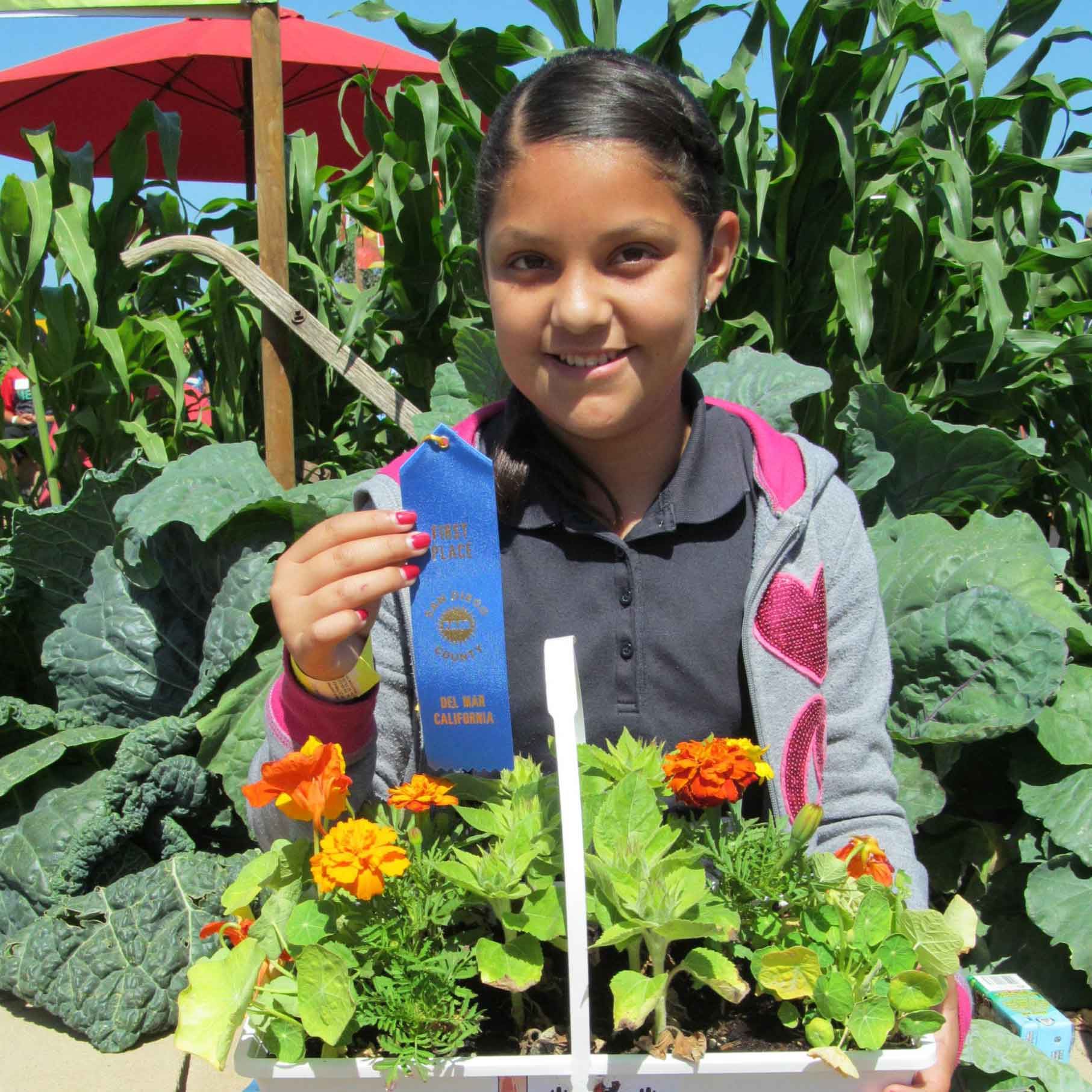 Student with hand-grown plant and award ribbon