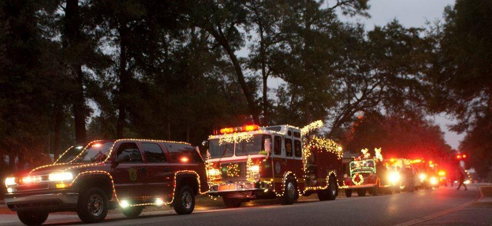 fire truck and 2 other vehicles with Christmas lights  traveling down a residential street
