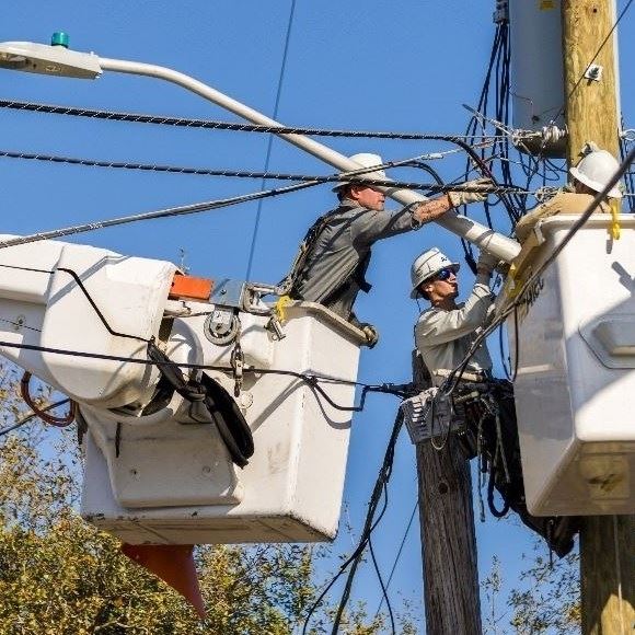 2 men on a boom truck at a power pole